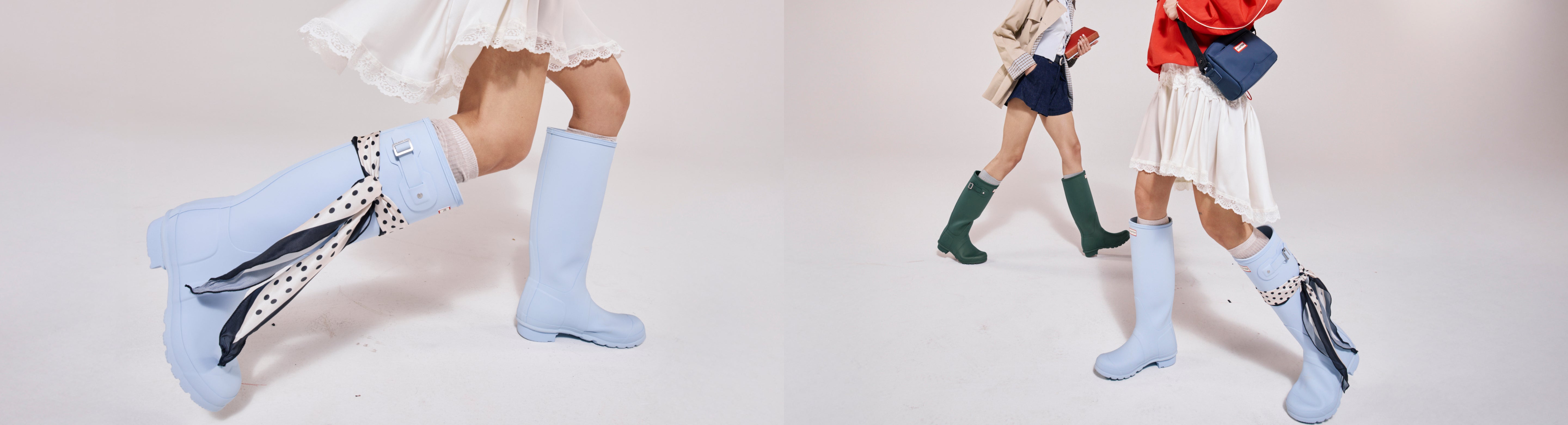 Models wearing Hunter Original tall rain boots in blue and green